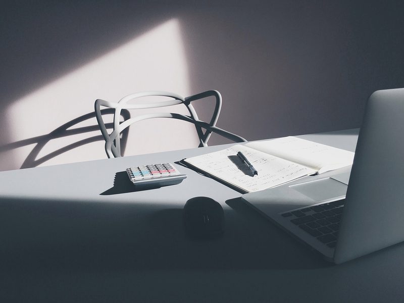 Laptop con calculadora y datos tabulados sobre un escritorio