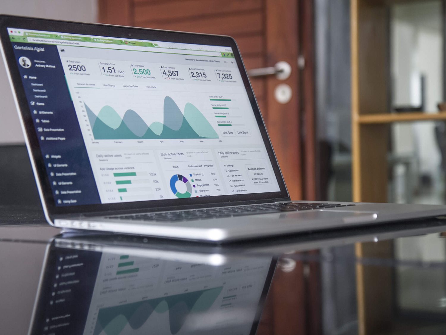Laptop con tablas y gráficos estadísticos sobre una mesa de trabajo