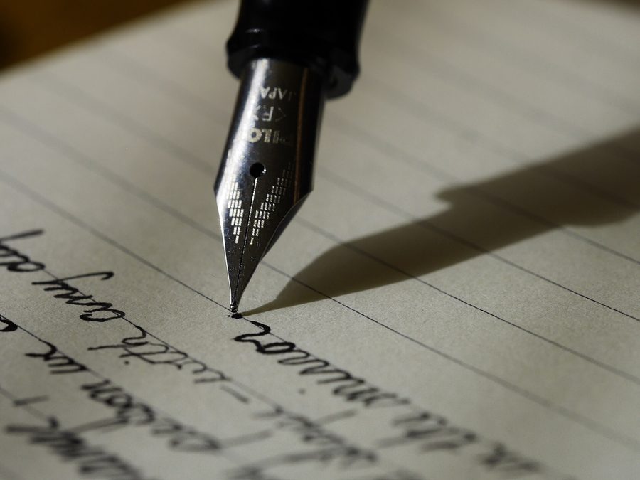 Mano escribiendo con pluma sobre un documento